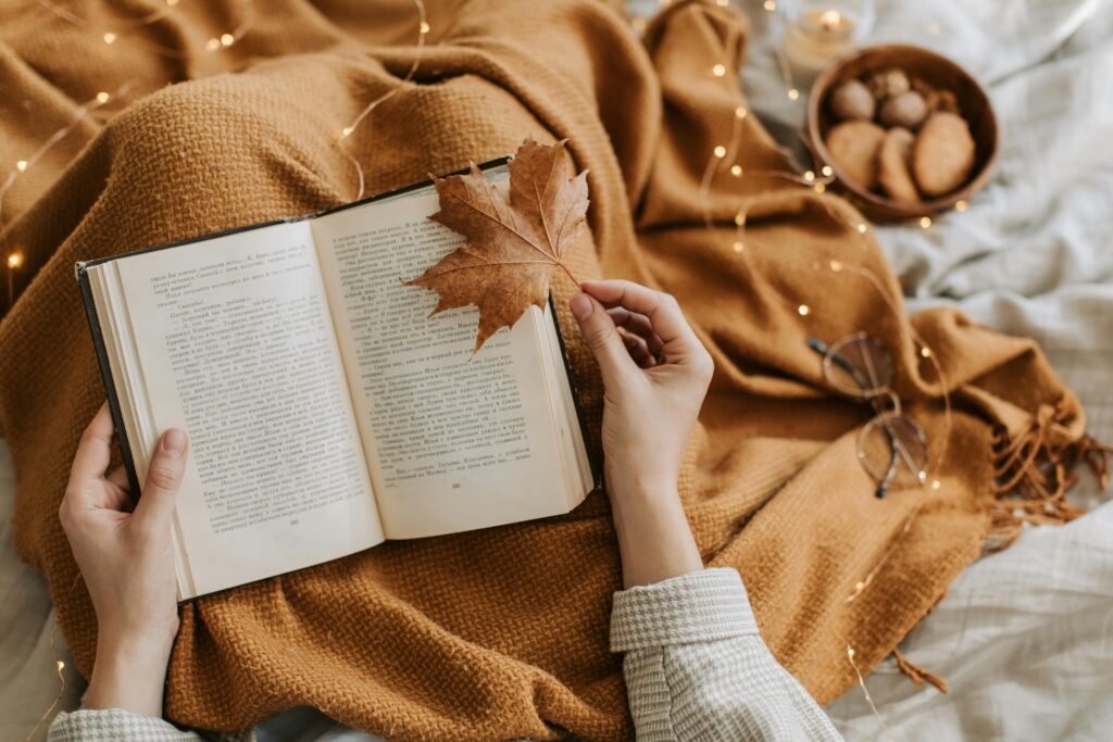 pexels-photo-9969154-9969154 A cozy autumn scene with a book, warm blanket, and cookies for a relaxing reading atmosphere.